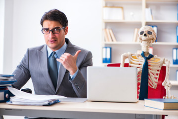 Businessman working with skeleton in office