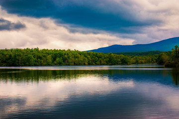 A cloudy sky reflects in the calm waters of an Appalachian lake in the mountains