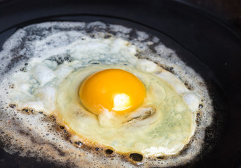 An fried egg in butter in a carbon steel frying pan
