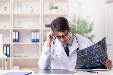 Young doctor looking at x-ray images in clinic