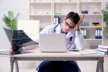 Young doctor looking at x-ray images in clinic