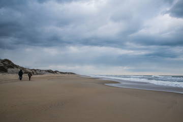 Walking down the beach under a cold stormy sky at Cape Hatteras National Seashore in North Carolina