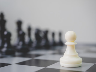 Strategic planning business competition concept. White pawn surrounded by black chess pieces on a chess board