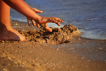 Marine background. A child is playing with sand on the beach. Abstract background. Selective focus. Close-up, side view, copy space.