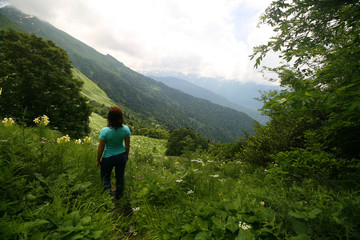 Fototapeta na wymiar Young woman among the flowering meadows in the Caucasus mountains