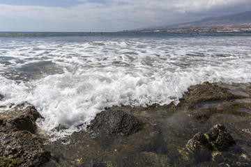Fototapeta na wymiar Beach in Las Americas. Beach for surfers, in Tenerife, Spain. Stone beach. Playa de las Americas, Tenerife.