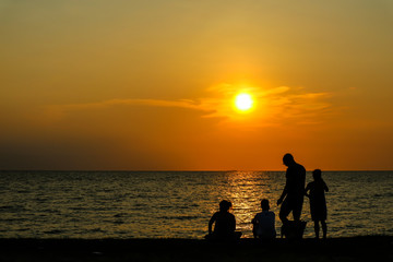 silhouette family play with one dog on beach sunset