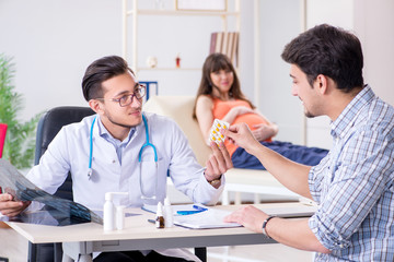 Fototapeta premium Pregnant woman with her husband visiting the doctor in clinic