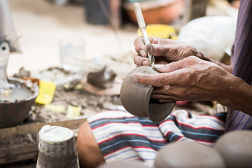 Fototapeta premium Closed-up hands of a old man to make pottery. Pottery is the ceramic material which makes up pottery wares, of which major types include earthenware, stoneware and porcelain.