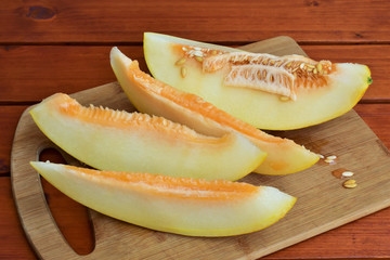 Ripe melon, sliced on a wooden board.