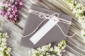 Gift box with a place for signature or wishes decorated with a twig and lilac on old wooden background. Flat lay styling. © yrabota
