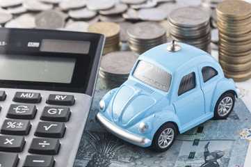 Close up blue car with calculator and coin.- Selective focus in car.- Image concept for car insurance and financial.
