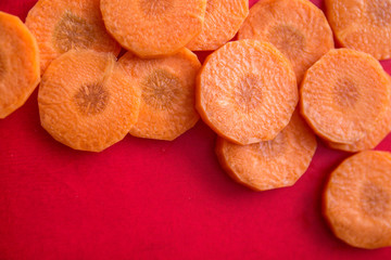copy space with round slices of fresh orange carrot on the edges of a bright red background