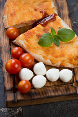 Closeup of sliced italian calzone pizza on a wooden serving tray, vertical shot, selective focus