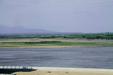 landscape with a green island with sandy beaches in a river and green forest and a mountain on the background