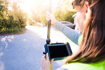 Close up of woman in reflective clothing using GPS land surveying tool with screen