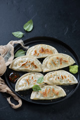 Metal tray with fried korean potstickers over black stone background, vertical shot, selective focus