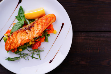 Delicious grilled salmon steak with vegetable garnishing. Restaurant seafood menu photo, copy space, property nutrition and healthy food concept