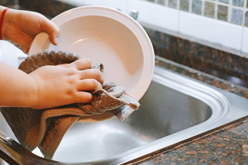 Hands in rubber gloves washing dishes with spon