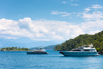 Two modern yachts in a picturesque sea Bay. The island and mountains in the background