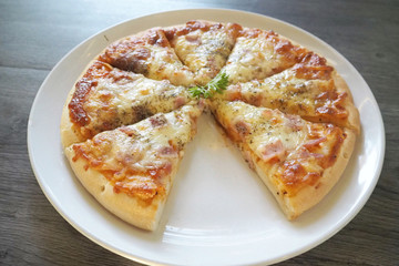 Bake Pizza ham and grilled mozzarella cheeses decorate on top with coriander on white dish with gray wooden ready to serve