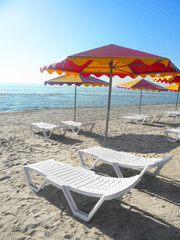 two sun loungers under an umbrella against the background of the sea