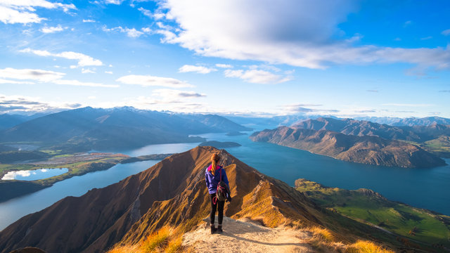A woman looking at the beautiful landscape of the mountains and Lake Wanaka. Roys Peak Track, South Island, New Zealand.
