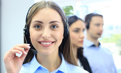 Portrait of call center worker accompanied by her team. Smiling customer support operator at work.