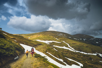 Fototapeta premium Family hikers walking by the road in a spring mountains