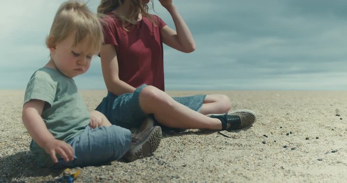 Toddler boy and his mother sitting on the beach