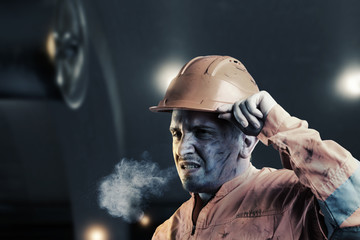 portrait of tired rail worker with orange unifom and helmet light in front of tunnel at night
