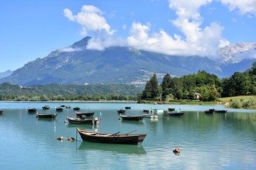 Fototapeta na wymiar Lago di montagna con tipiche barche per turisti