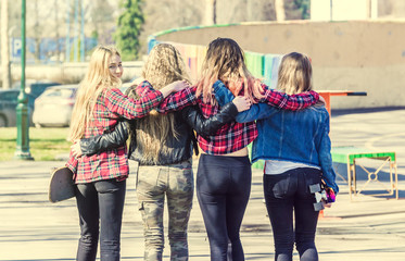 Back view of four girl friends hugging