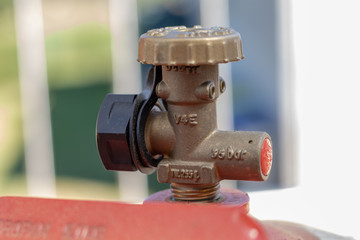 Metallventil einer Gasflasche an einem Gasgrill im Garten