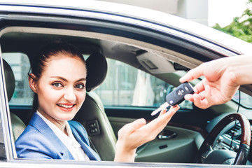 Sales dealer giving car keys to new car with business woman smiling while sitting in a car.sale and rental car concept