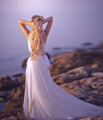 Beautiful girl in a long white wedding dress in Greek style is the old Greek goddess