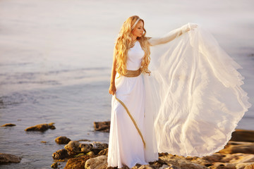 Beautiful girl in a long white wedding dress in Greek style is the old Greek goddess