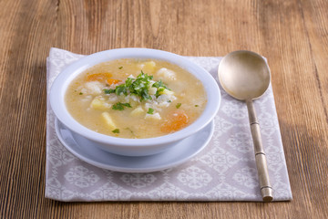 Fresh vegetable soup made of carrot, potato, cauliflower, parsley and rice in white plate,