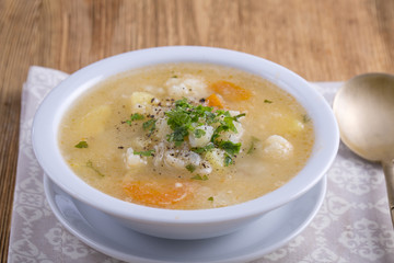 Fresh vegetable soup made of carrot, potato, cauliflower, parsley and rice in white plate,