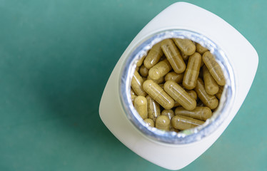 top view of herb capsules in white bottle.