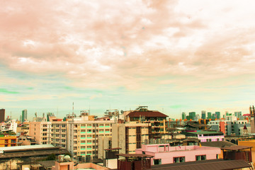 Bird view over cityscape and construction site including several cranes working on a building complex, with sun and clouds in the morning.Copy space.Bangkok.Pastel tone.
