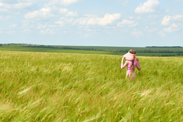 Fototapeta na wymiar child walking through the wheat field, bright sun, beautiful summer landscape