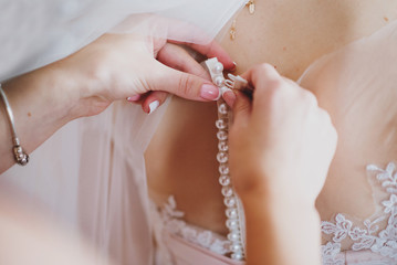 Bridesmaid dressing bride on wedding, closeup
