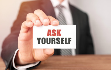Businessman holding a card with text Ask Yourself