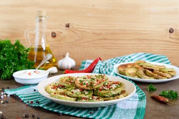 Fried circles of young zucchini with garlic, red pepper, greens on a plate. Vegetarian menu.