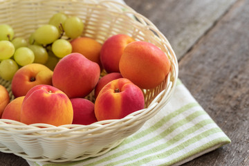 Ripe sweet fresh apricots in a basket on the wooden table.