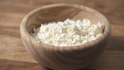 closeup crumbly cottage cheese in wood bowl