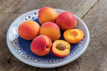 Juicy delicious ripe apricots on a plate. Natural wooden background.