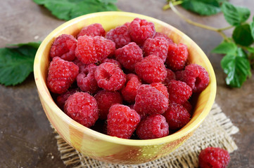 Fresh ripe tasty raspberries in a yellow ceramic bowl. Summer berries.
