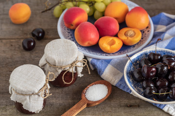 Homemade jam with fresh fruits over on wooden table. Rustic style.